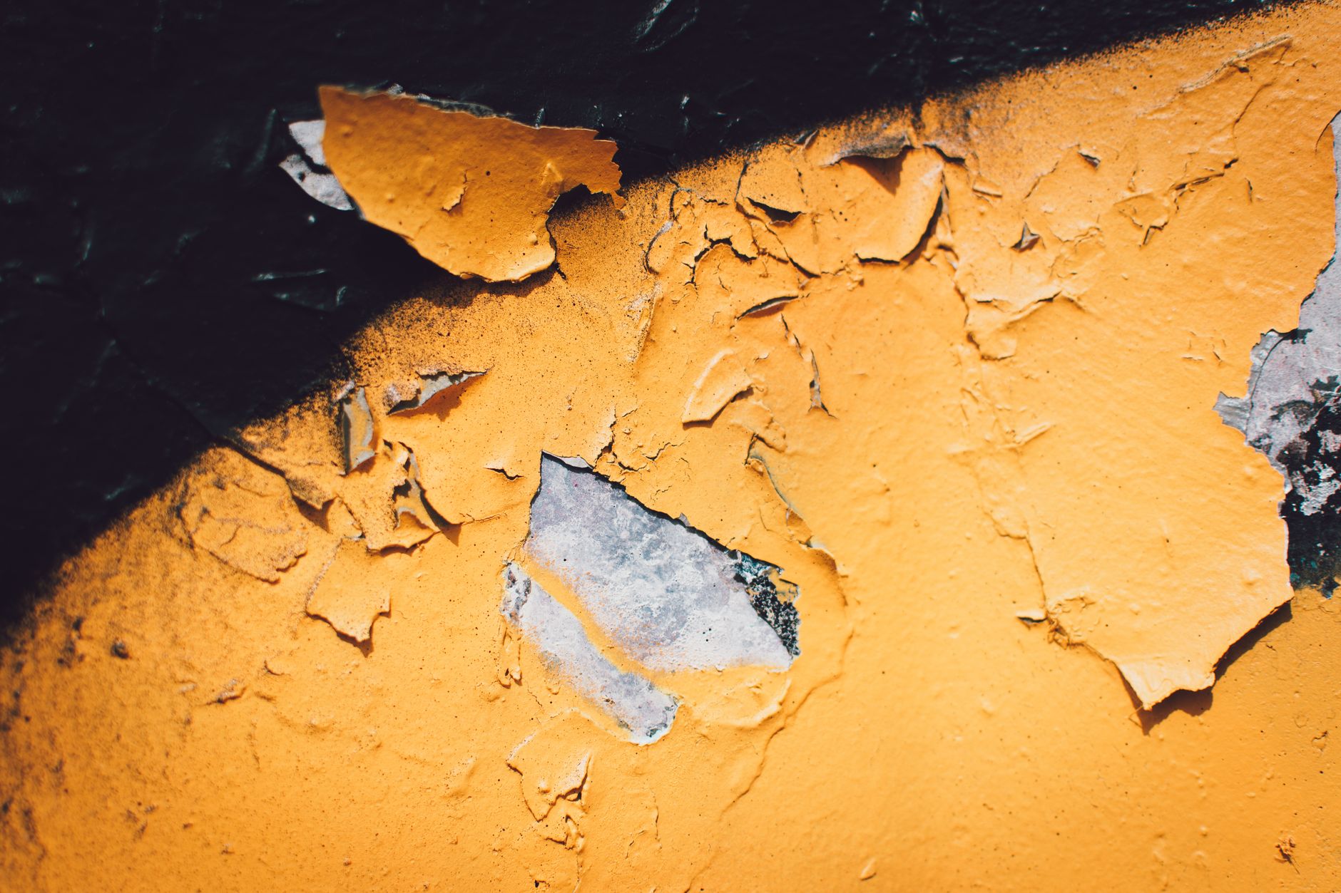 A detailed close-up of peeling yellow paint on a textured wall with visible decay in Torrance, CA